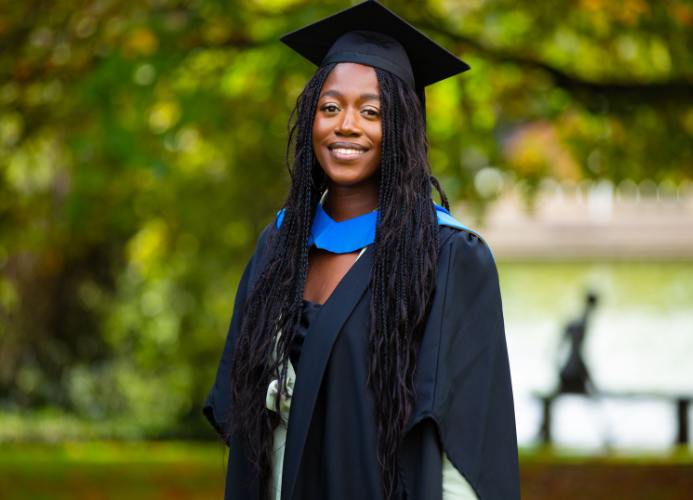 Anu Bode Favours posing for a graduation photo by the main lake.